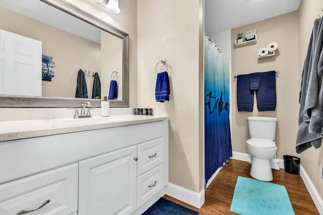 bathroom with toilet, vanity, and hardwood / wood-style flooring