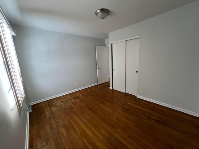 unfurnished bedroom featuring dark hardwood / wood-style flooring and a closet