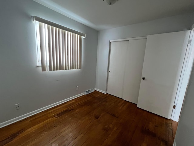 unfurnished bedroom with dark hardwood / wood-style floors and a closet