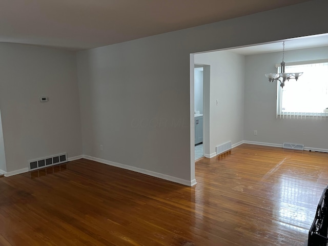 unfurnished room with hardwood / wood-style flooring and a chandelier