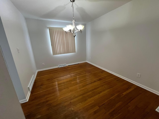 empty room featuring dark hardwood / wood-style flooring and a chandelier