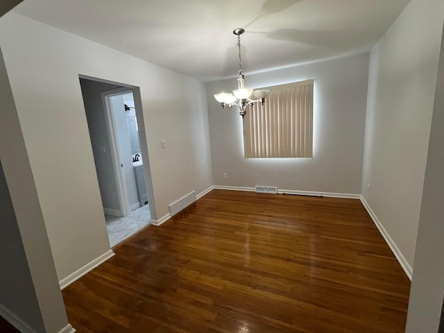 unfurnished dining area with dark hardwood / wood-style floors and an inviting chandelier