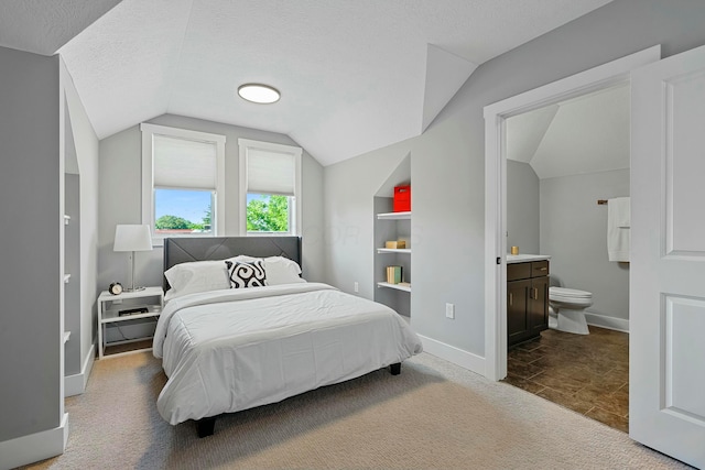 bedroom featuring carpet, lofted ceiling, a textured ceiling, and connected bathroom