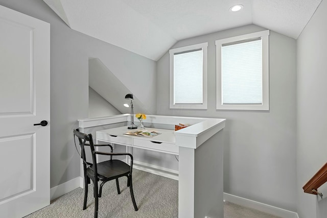 office space featuring a textured ceiling, light colored carpet, and vaulted ceiling