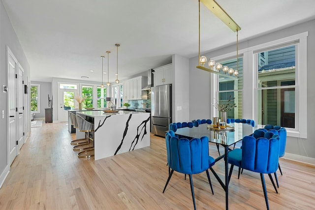 kitchen featuring a kitchen bar, stainless steel fridge, tasteful backsplash, decorative light fixtures, and white cabinetry