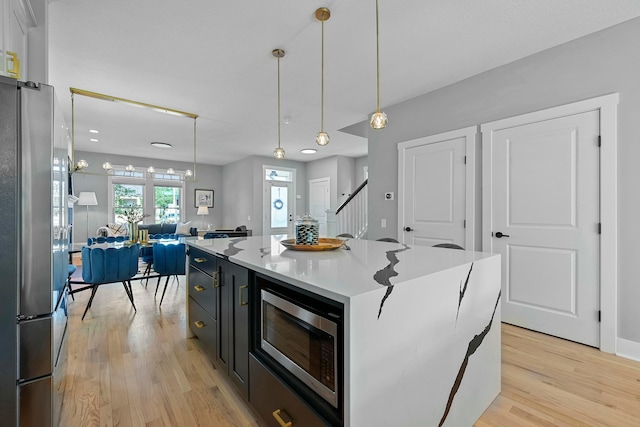 kitchen featuring appliances with stainless steel finishes, light hardwood / wood-style floors, a kitchen island, and pendant lighting