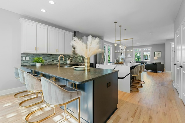 kitchen with white cabinets, decorative backsplash, a breakfast bar area, and sink