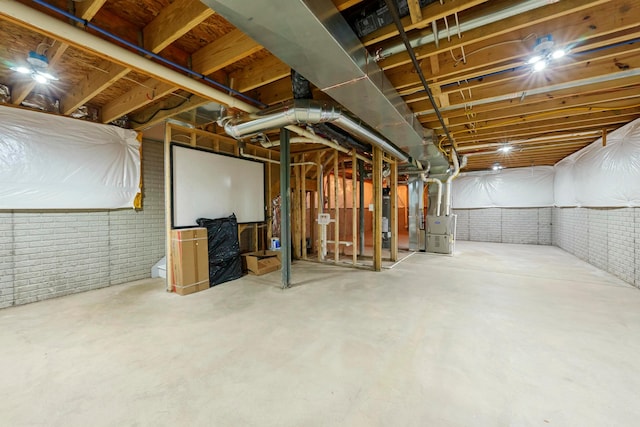 basement featuring brick wall and heating unit