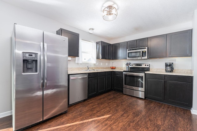 kitchen featuring a textured ceiling, dark wood-type flooring, appliances with stainless steel finishes, and sink