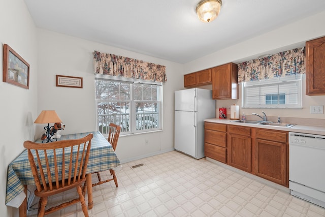 kitchen with white appliances, light countertops, a sink, and light floors