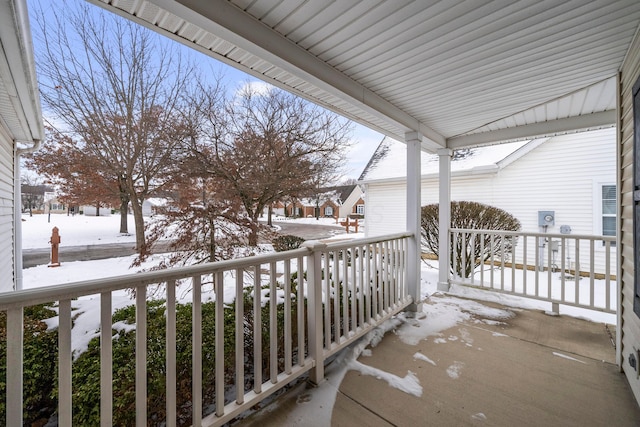 snow covered back of property with covered porch