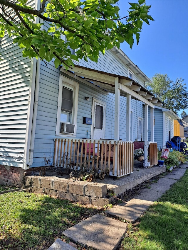 view of exterior entry featuring covered porch and cooling unit