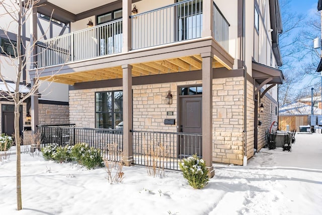 snow covered property entrance with a balcony