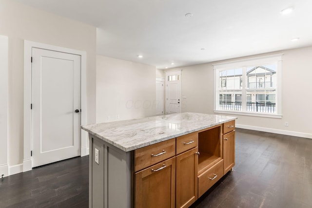 kitchen with a center island, dark hardwood / wood-style flooring, and light stone countertops