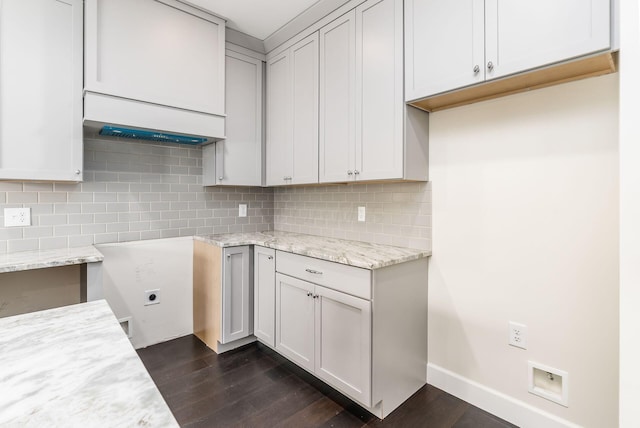 kitchen featuring light stone countertops, backsplash, dark hardwood / wood-style floors, and white cabinetry