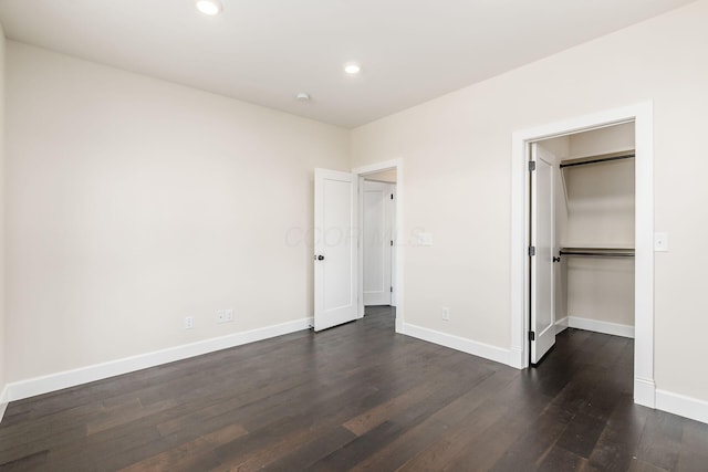 unfurnished bedroom with a spacious closet, a closet, and dark hardwood / wood-style floors