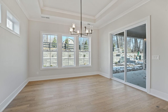 unfurnished dining area with a raised ceiling, ornamental molding, and light wood-type flooring