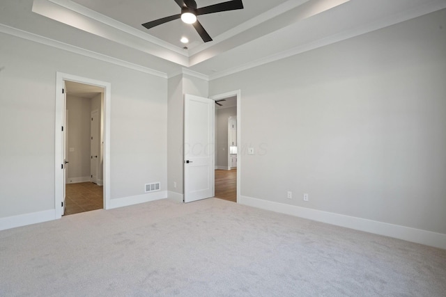 unfurnished bedroom with crown molding, carpet flooring, ceiling fan, and a tray ceiling