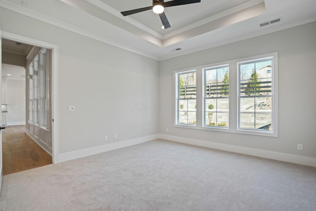 carpeted spare room featuring crown molding, ceiling fan, and a tray ceiling