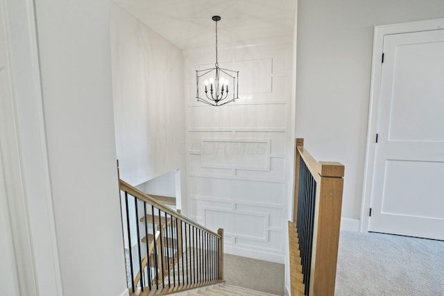 staircase with a chandelier and carpet flooring