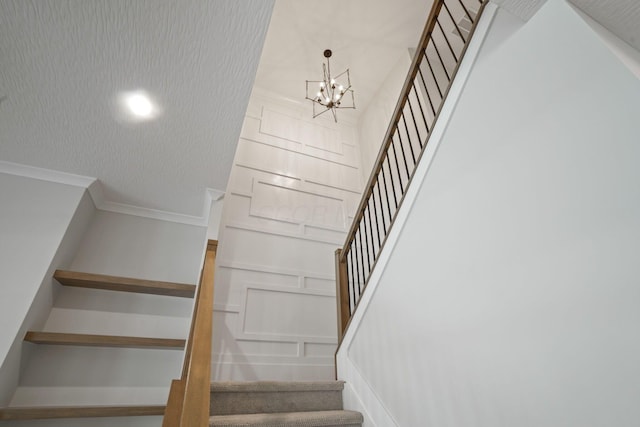 stairs featuring an inviting chandelier and ornamental molding