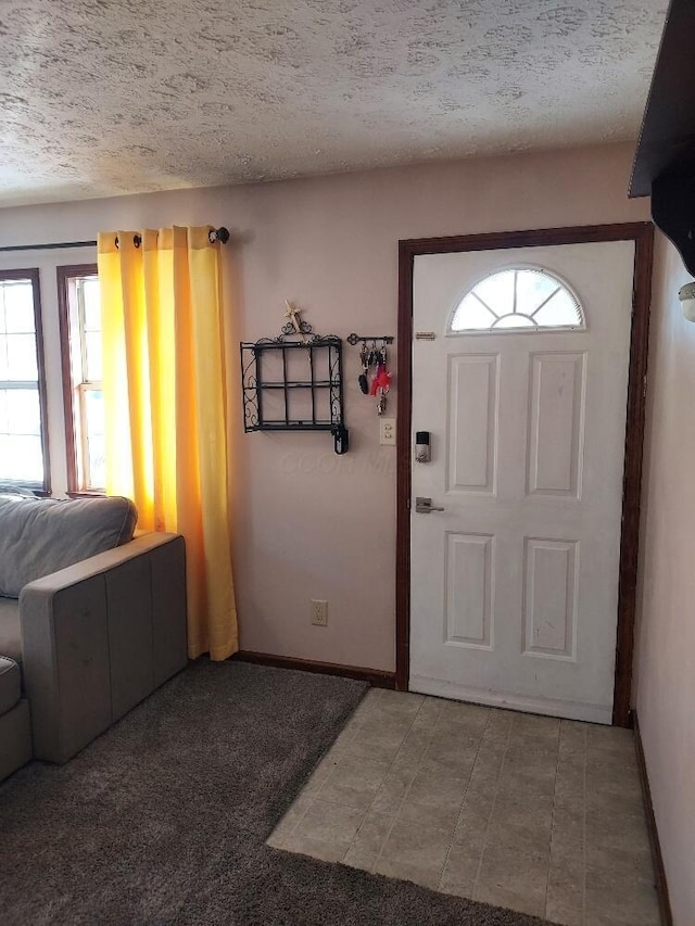 carpeted foyer featuring a textured ceiling