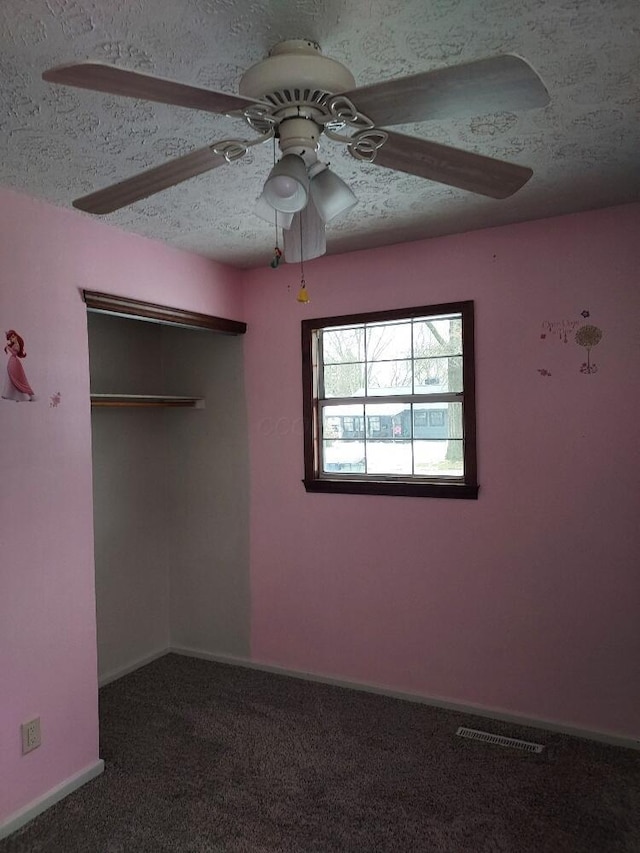 unfurnished bedroom with ceiling fan, a closet, dark carpet, and a textured ceiling