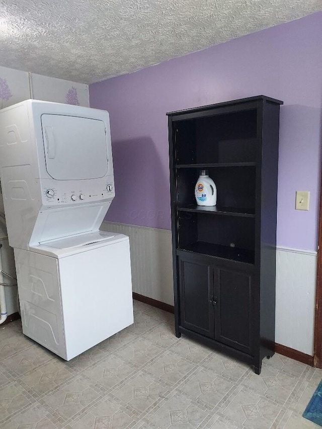 washroom with a textured ceiling, wood walls, and stacked washer and dryer