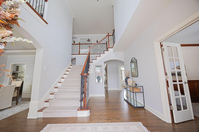 foyer entrance featuring a towering ceiling, dark hardwood / wood-style flooring, french doors, and ornamental molding