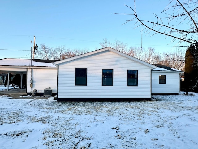 snow covered back of property featuring central air condition unit