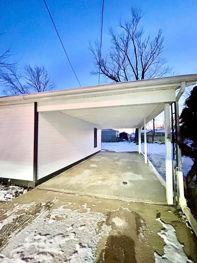 snow covered parking area with a carport