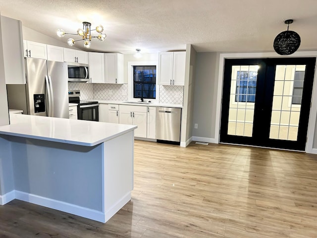 kitchen with decorative light fixtures, backsplash, white cabinetry, and appliances with stainless steel finishes