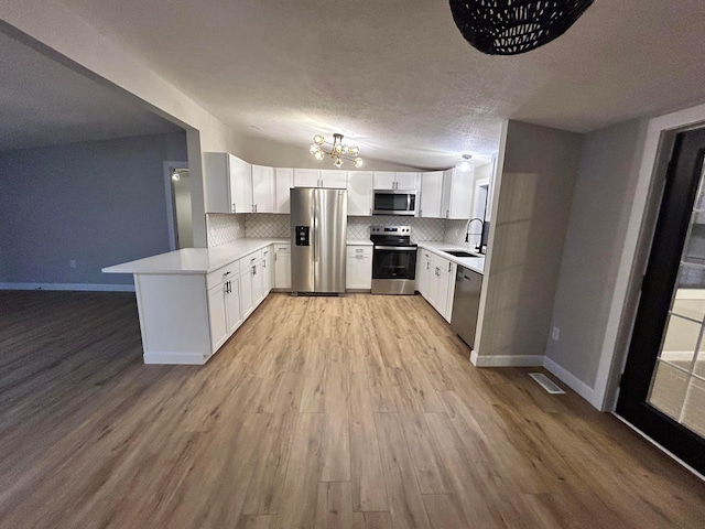 kitchen featuring a textured ceiling, appliances with stainless steel finishes, white cabinetry, tasteful backsplash, and kitchen peninsula