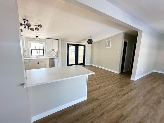 kitchen featuring white cabinetry, dark hardwood / wood-style floors, tasteful backsplash, dishwasher, and french doors