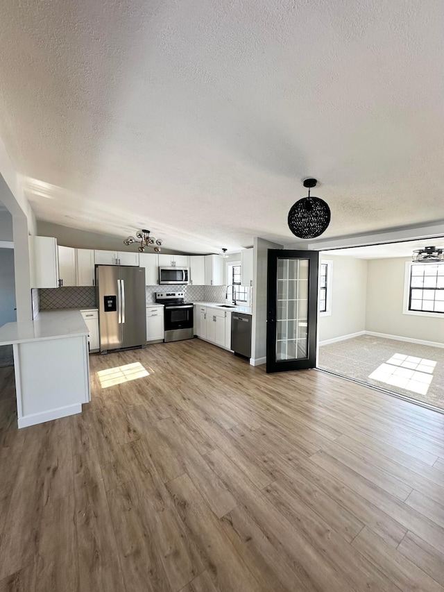 unfurnished living room featuring a textured ceiling, light hardwood / wood-style floors, and sink