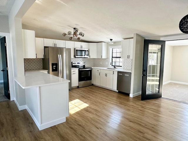 kitchen with stainless steel appliances, light hardwood / wood-style flooring, white cabinetry, and sink