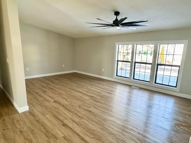 spare room with light wood-type flooring, ceiling fan, and a wealth of natural light