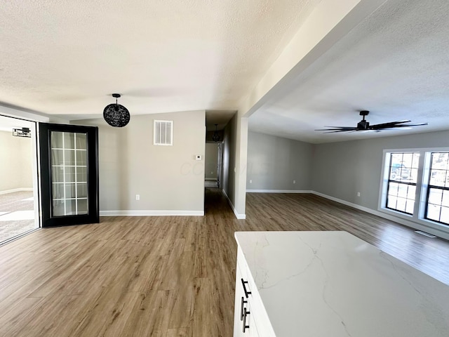 unfurnished living room featuring ceiling fan, a textured ceiling, and hardwood / wood-style floors