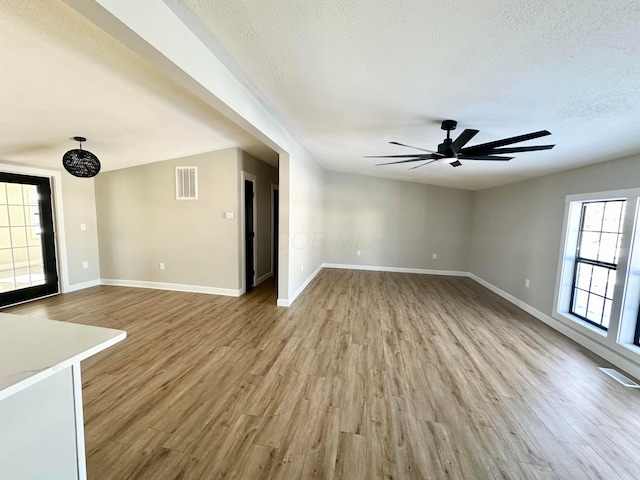 unfurnished living room with light wood-type flooring, ceiling fan, and a textured ceiling