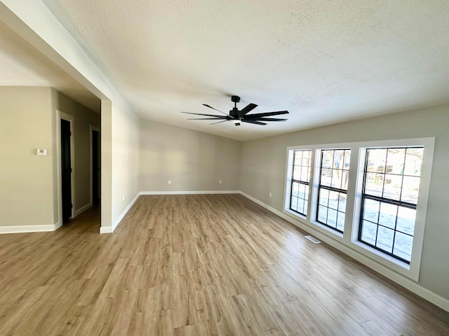 empty room featuring ceiling fan, light wood-type flooring, and a textured ceiling