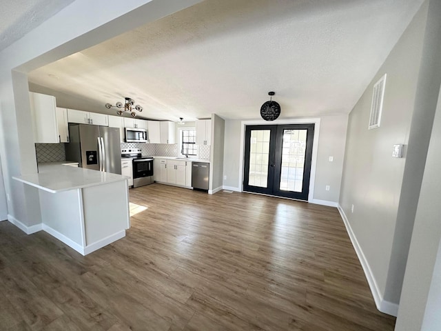 kitchen with white cabinets, appliances with stainless steel finishes, french doors, backsplash, and kitchen peninsula