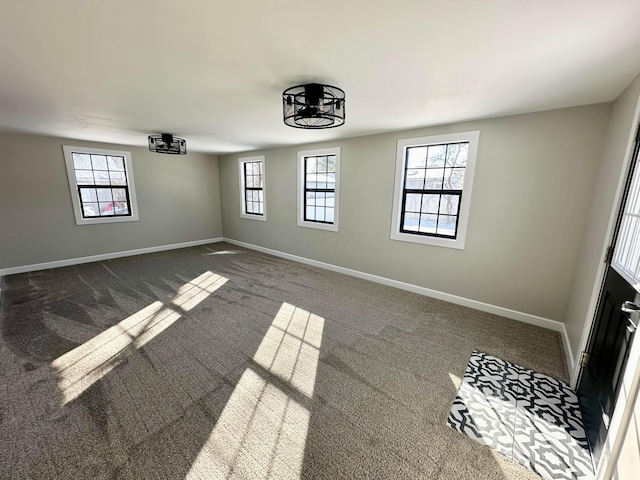 spare room with dark colored carpet, a chandelier, and a healthy amount of sunlight