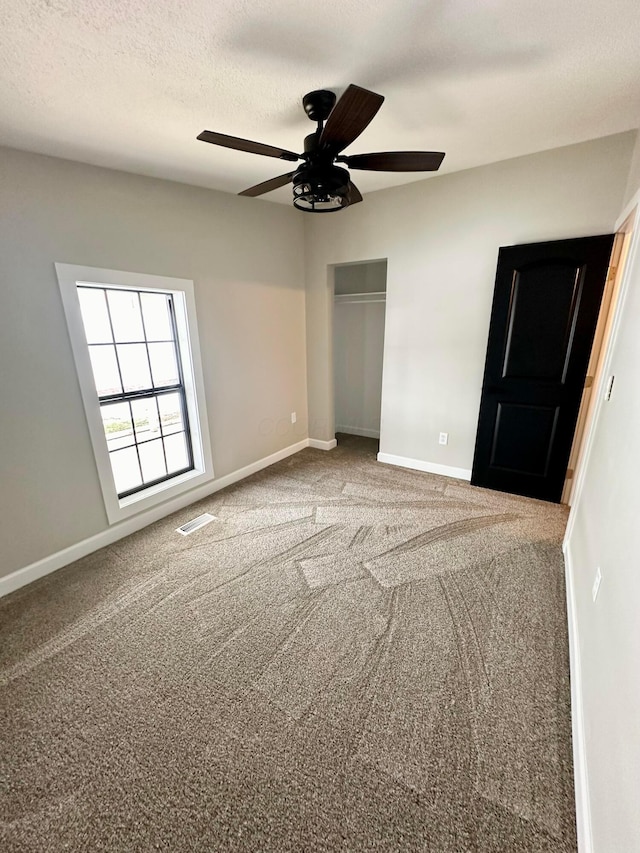 unfurnished bedroom featuring ceiling fan, a textured ceiling, and carpet flooring