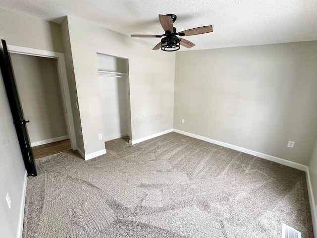 unfurnished bedroom featuring ceiling fan, a textured ceiling, a closet, and carpet floors