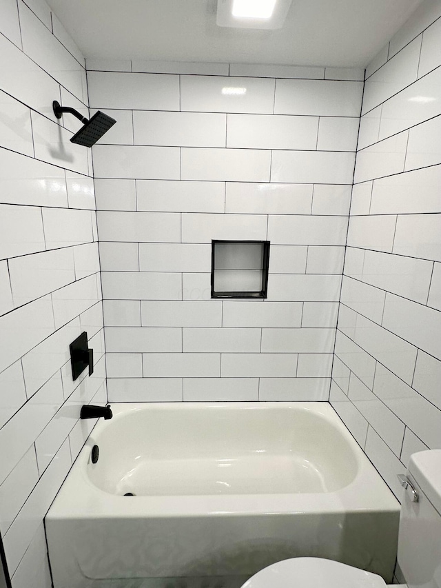 bathroom featuring toilet and tiled shower / bath combo