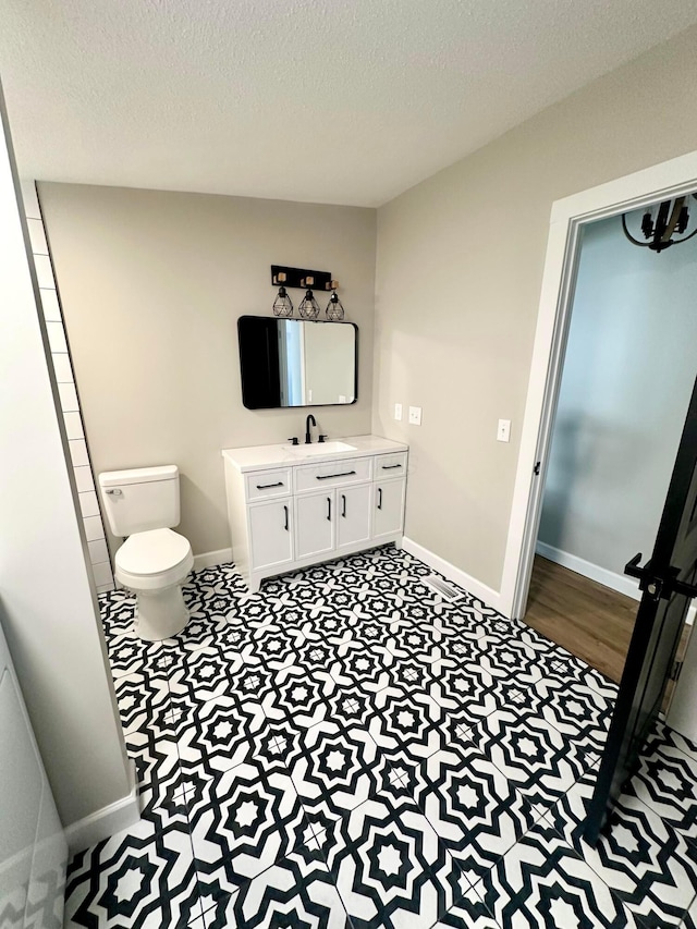 bathroom featuring toilet, vanity, and a textured ceiling