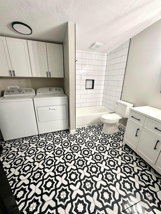 bathroom featuring toilet, vanity, washer and dryer, tiled shower, and a textured ceiling