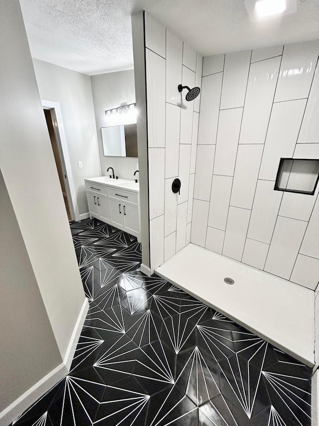 bathroom with a textured ceiling, a shower, and vanity