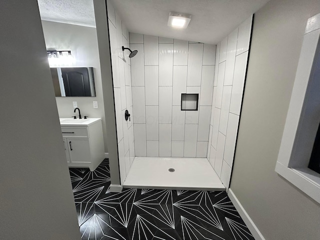 bathroom featuring a textured ceiling, vanity, and a tile shower