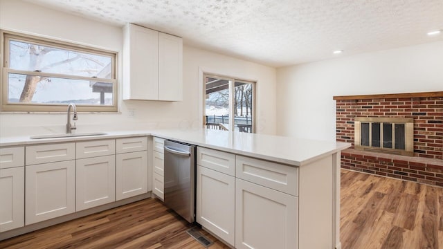 kitchen featuring kitchen peninsula, a textured ceiling, sink, white cabinets, and hardwood / wood-style floors